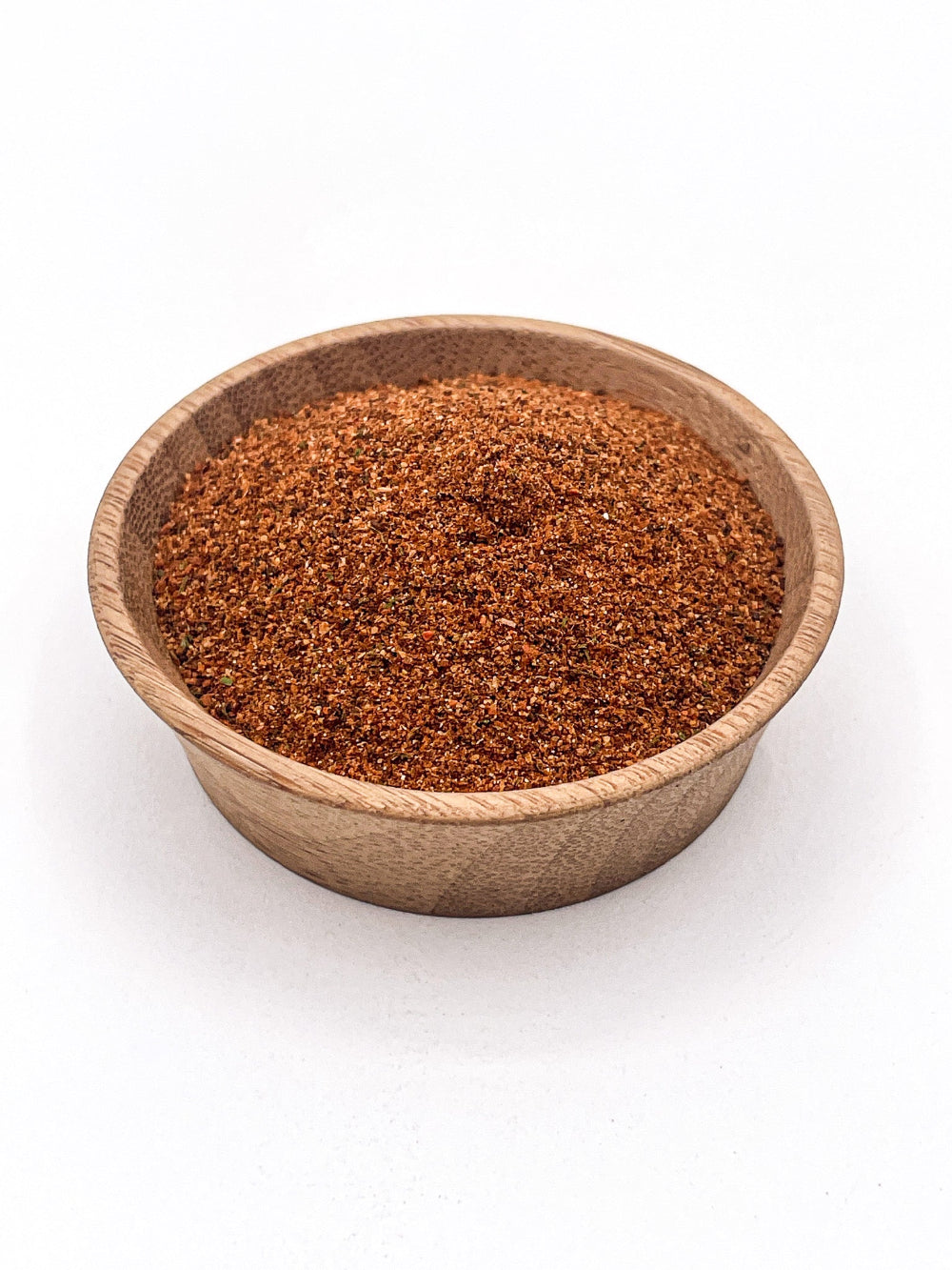 Wooden bowl filled with brown spice mix on a white background